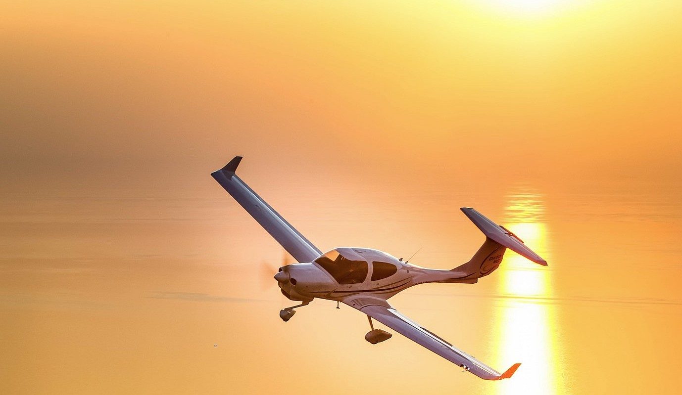 Diamond DA40NG aircraft flying over the sea at sunset